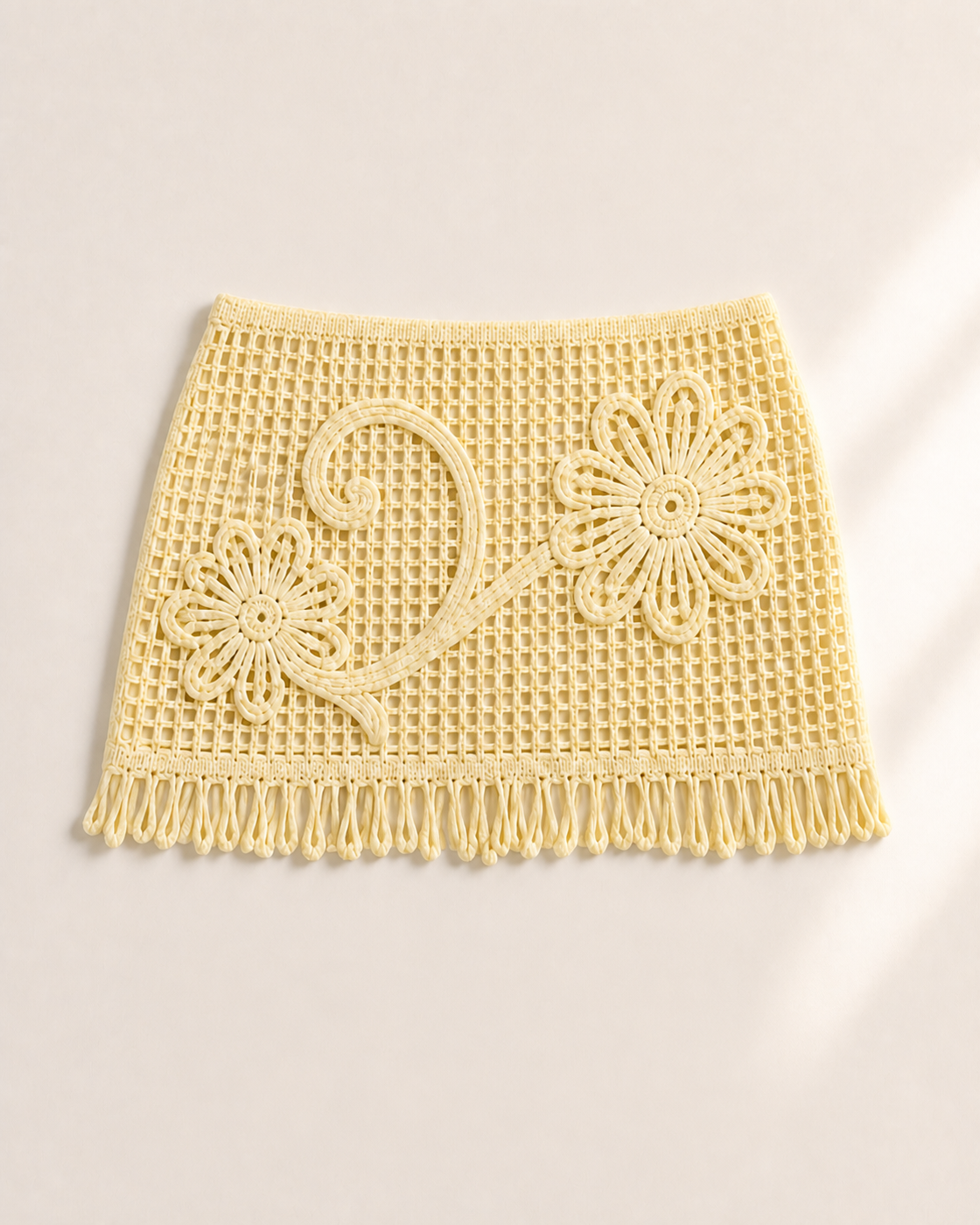 Pale yellow crochet fringe mini skirt with floral vine detail, studio product view