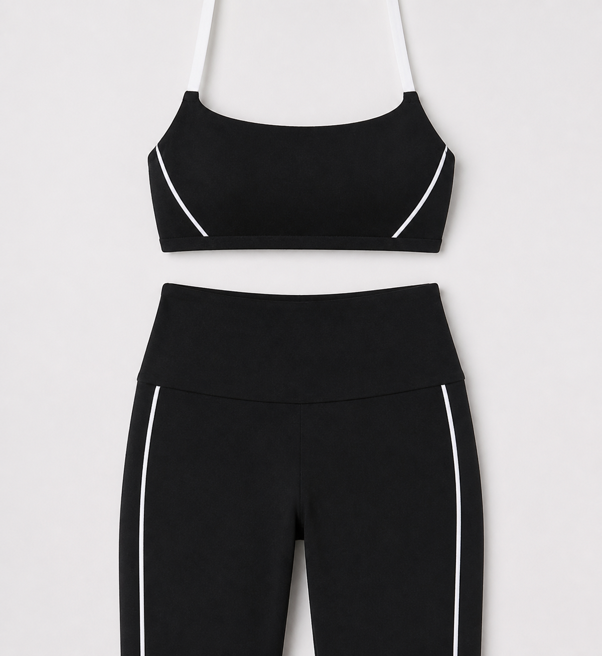 Black sports bra and flare pants detail showing white straps and curved side lines.