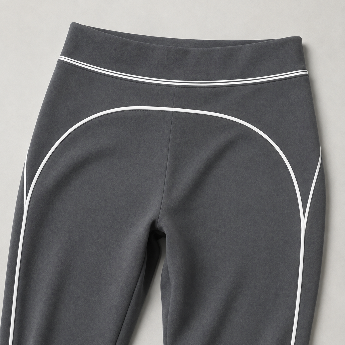 Charcoal gray leggings waistband and curved white contrast piping, shown in a product detail view.