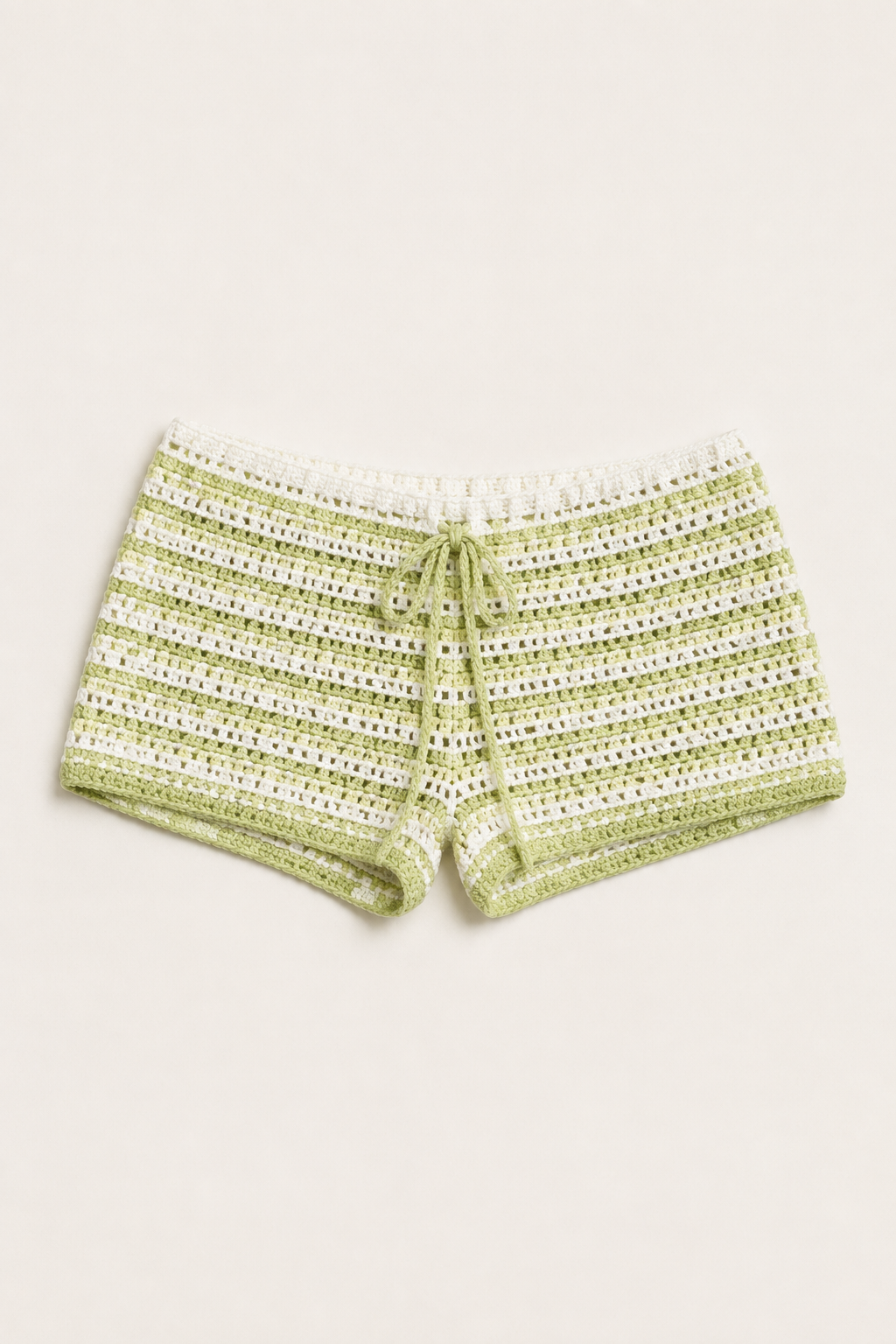 Pale lime green and ivory striped crochet shorts shown alone in a studio flat lay