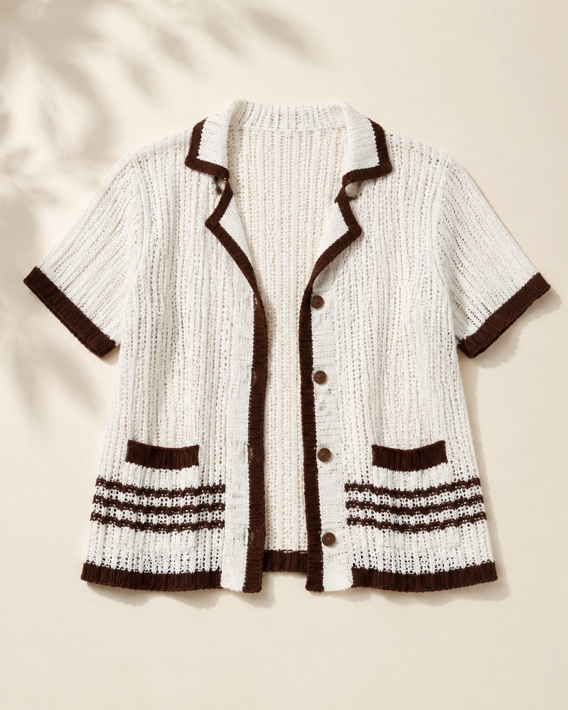 White openwork cardigan with brown trim and stripes, studio view