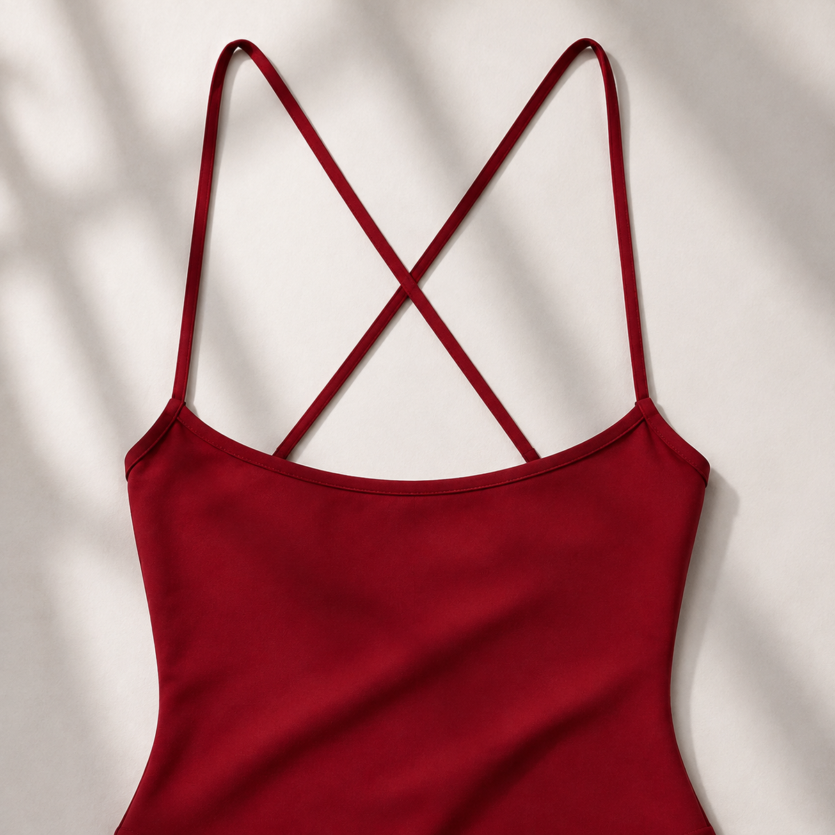 Close-up of the burgundy athletic romper showing its softly scooped neckline and thin shoulder straps.